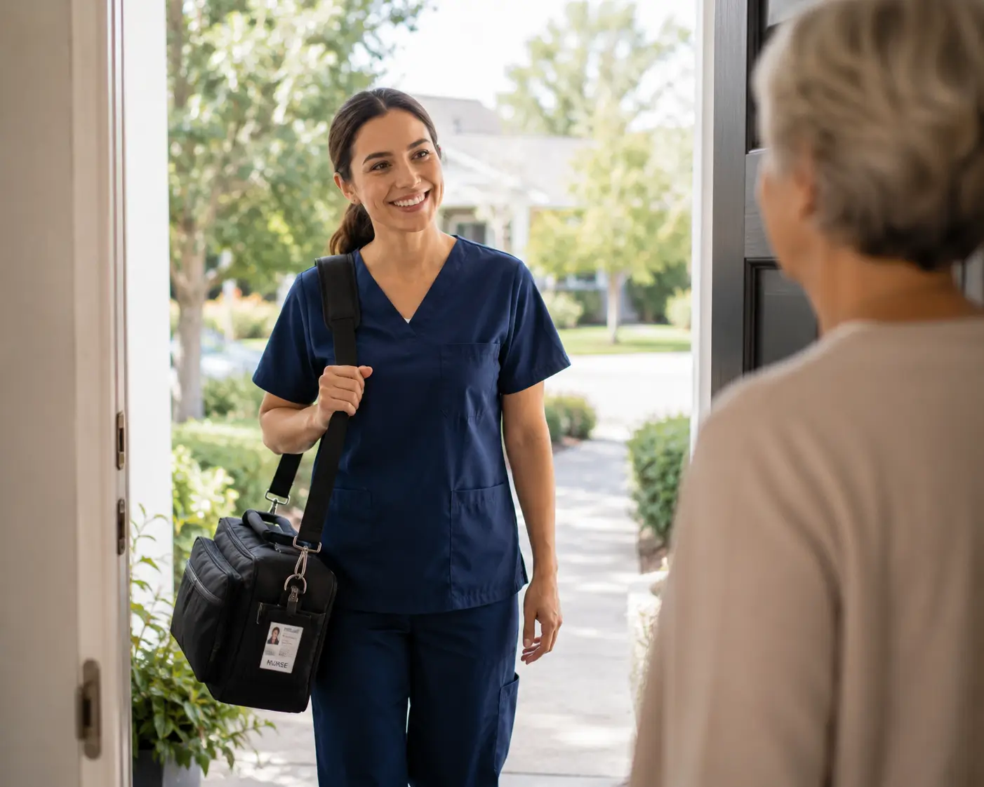 Une infirmière souriante en blouse bleue portant un sac médical arrivant à la porte d'entrée d'un patient.